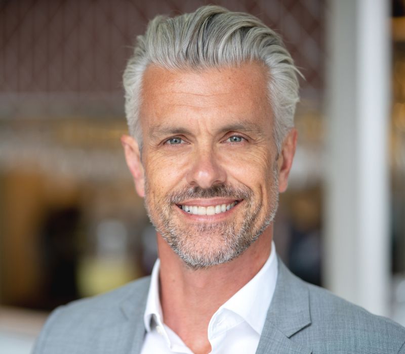 male med spa patient model in a gray suit jacked smiling