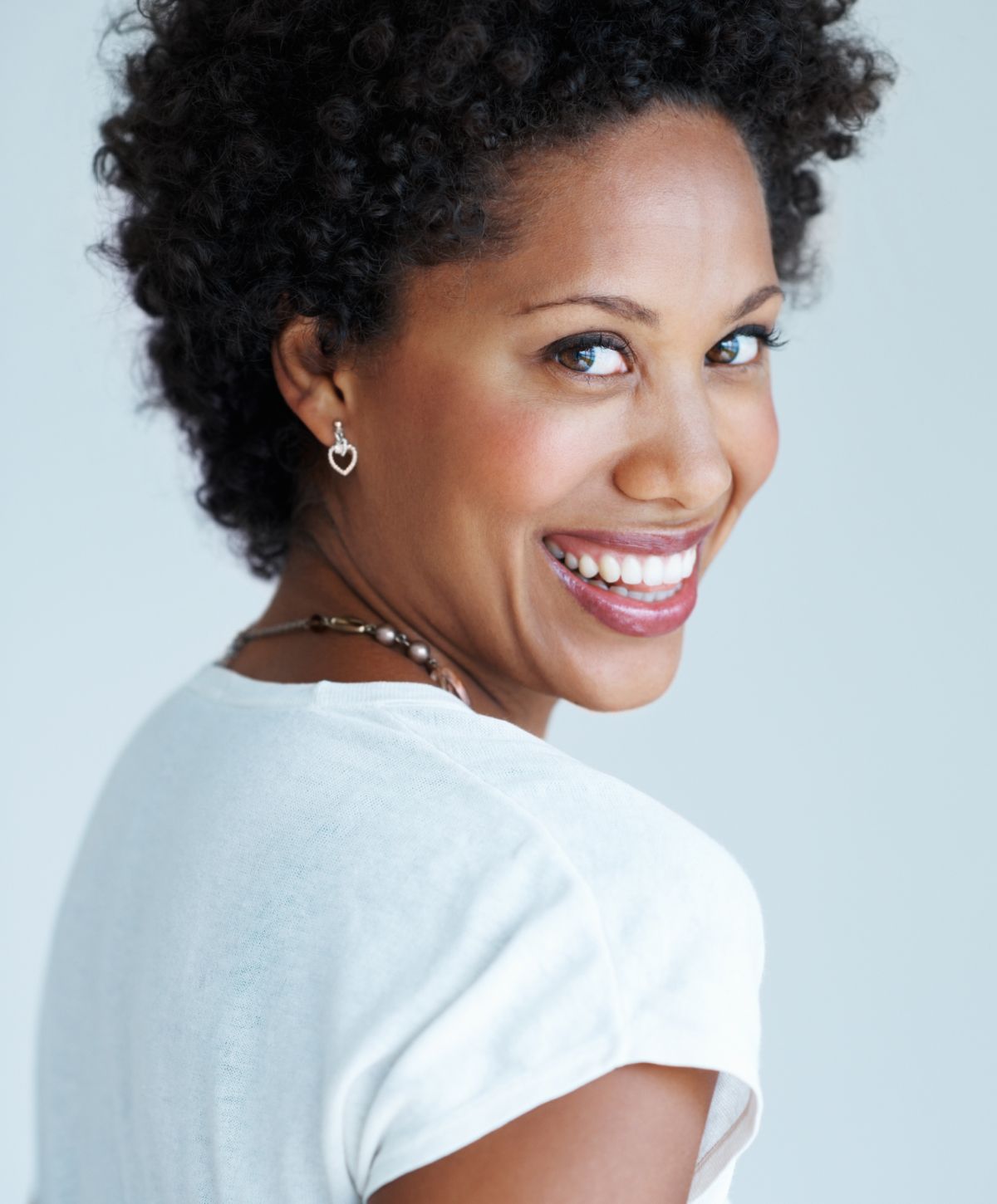 med spa patient model in a white shirt smiling over her shoulder