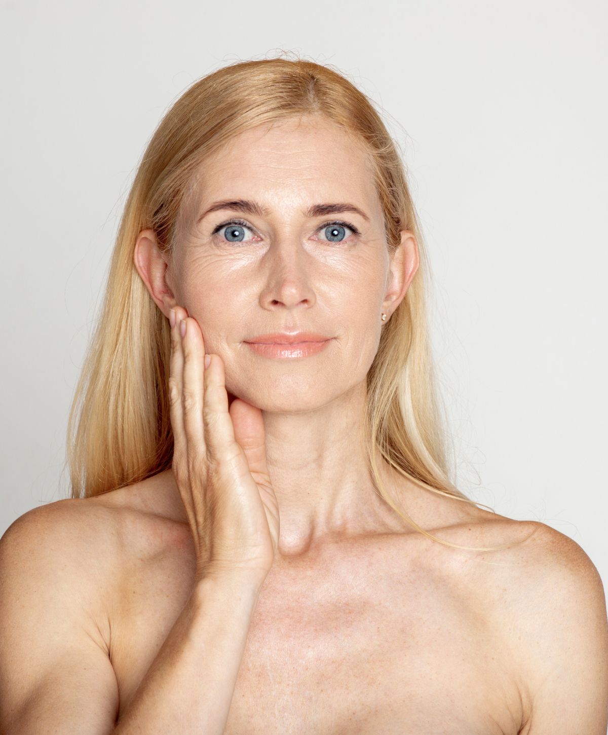 Woman with blonde hair touching her face.